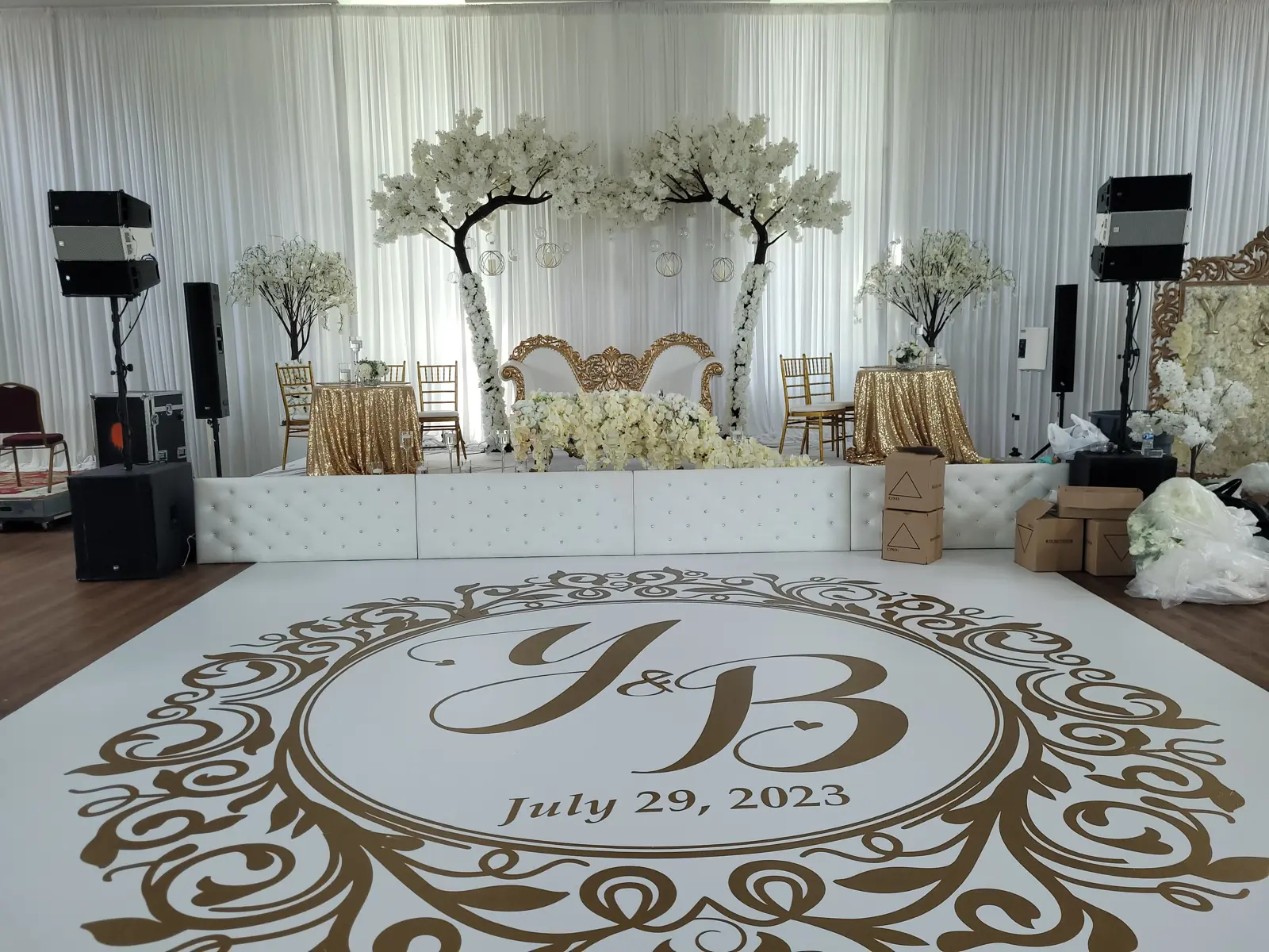 Wedding head table with tufted white backdrop, cherry blossom arch, and monogrammed dance floor