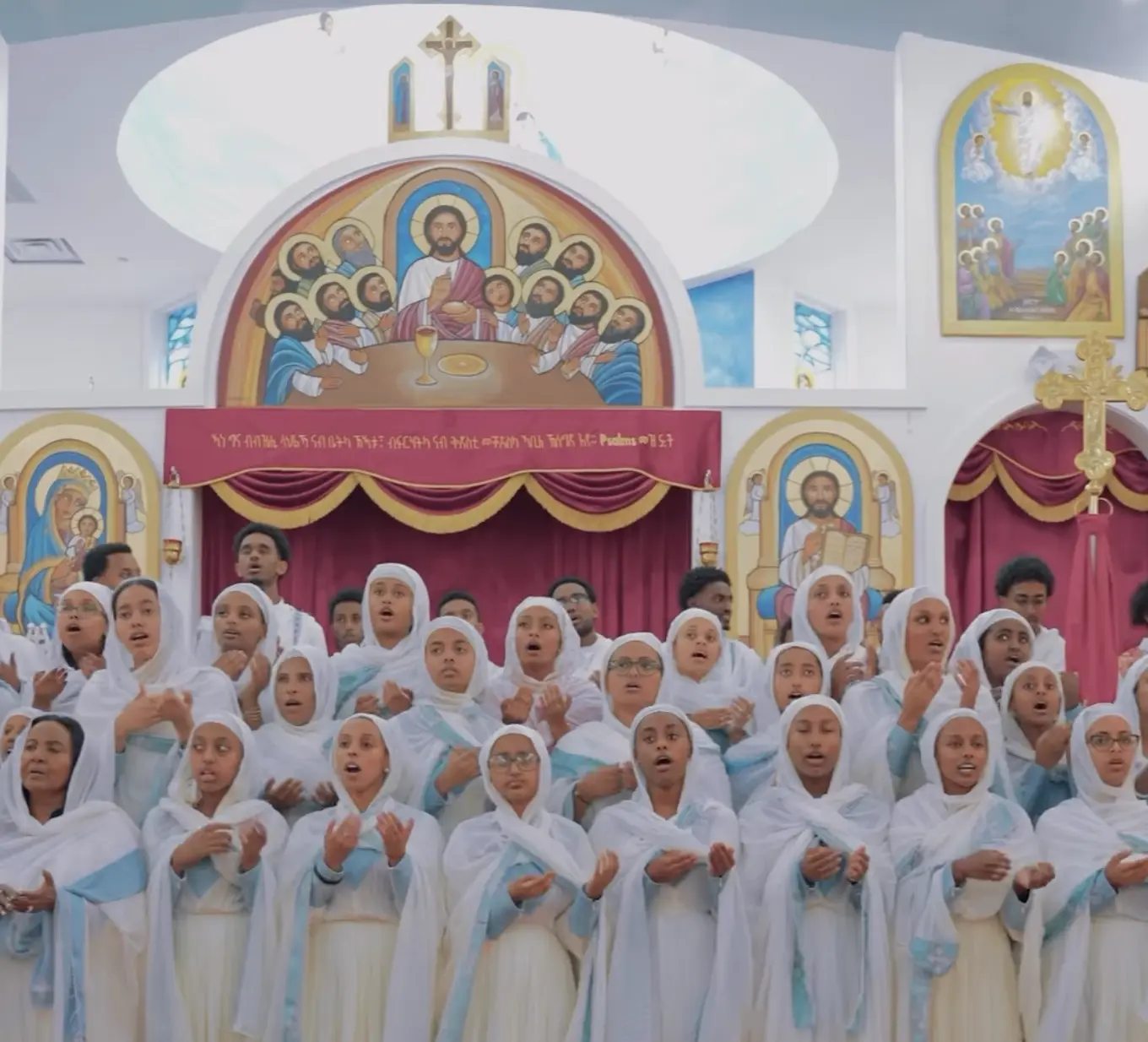 Youth choir in white garments singing in front of the altar iconography at Medhane Alem Church